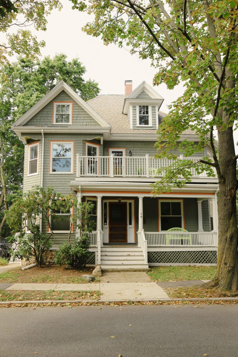 Unrecognizable passenger sitting on backseat and browsing smartphone while holding handle inside of yellow cab with lowered window during ride