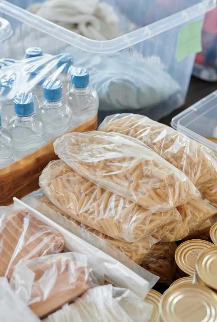 Packed groceries and canned food ready for donation. Includes pasta, water bottles, and bread.
